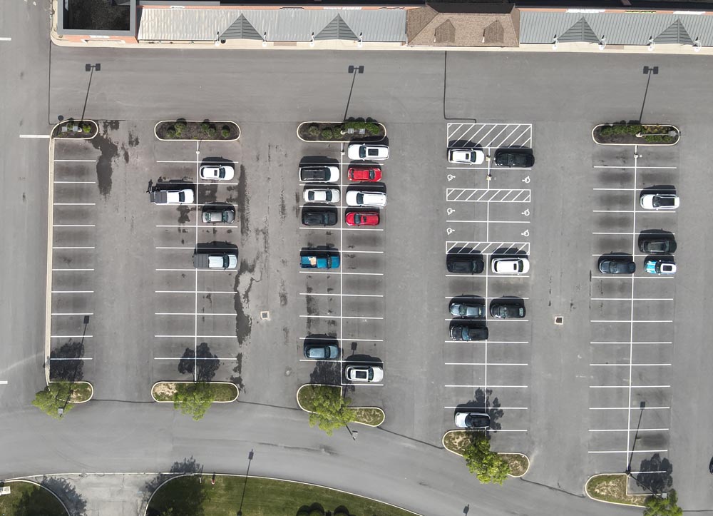 Overhead drone photograph of a commercial property showing parking lots and paved surfaces for pavement maintenance and capital planning.