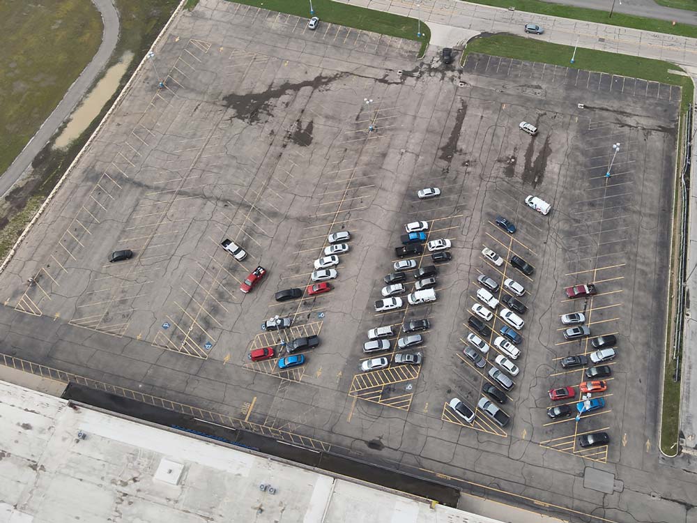 Overhead aerial view of a large commercial parking lot showing paved areas, parking sections, and access roads for pavement zone assessment.