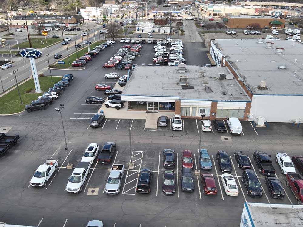 Aerial photograph of a commercial shopping center showing parking lots and paved areas for pavement project planning and documentation.