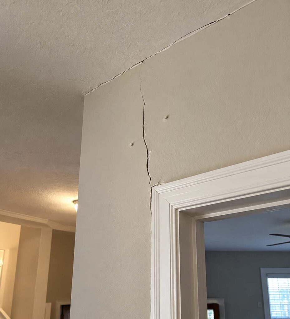Drywall cracks along a ceiling joint and above a doorway, with visible nail pops in a residential home in Central Ohio.