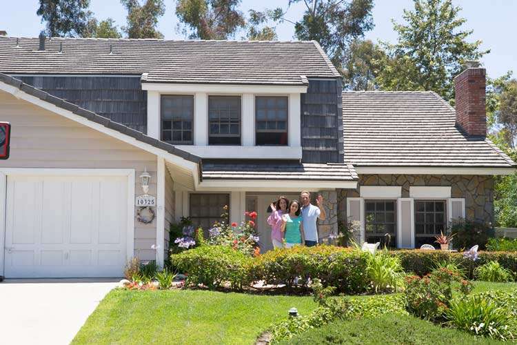 Small family standing in front of a new home