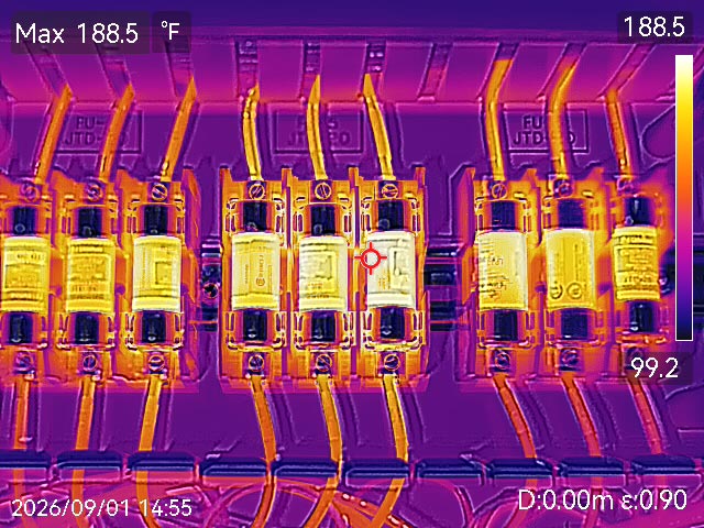 Thermal image of electrical breaker bank showing multiple breakers with scattered bright yellow and orange hotspots indicating uneven heating and potential fire hazards across the distribution array.