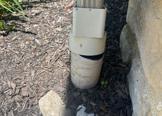 Downspout extension near a home's foundation during an inspection